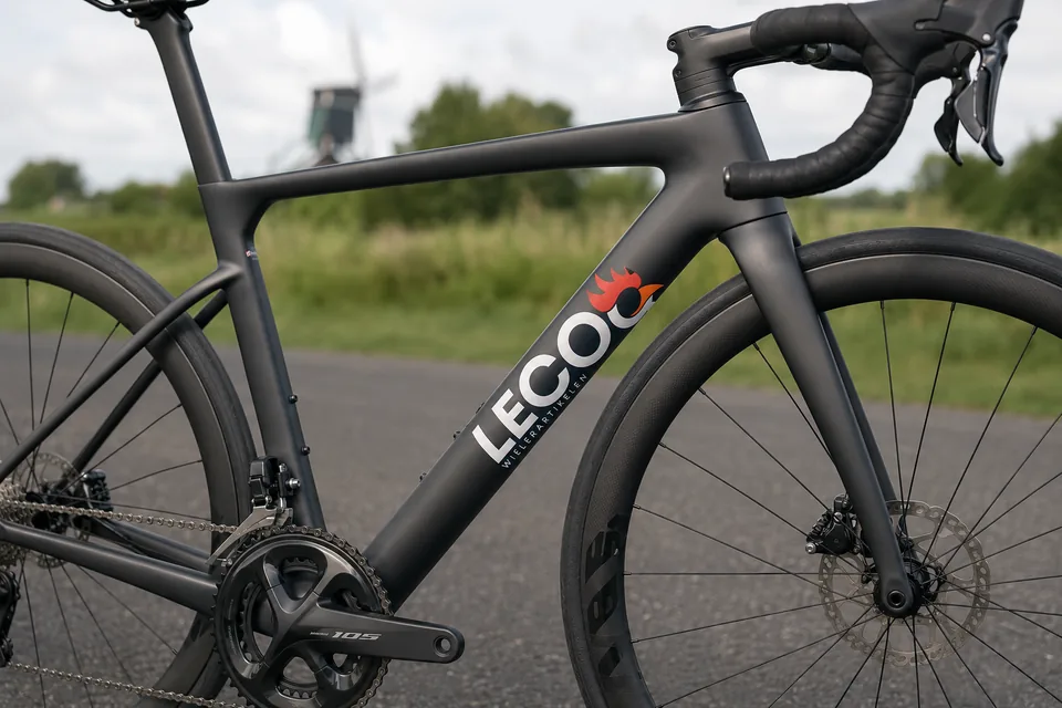 Belettering met LECOO-logo op het frame van een racefiets.